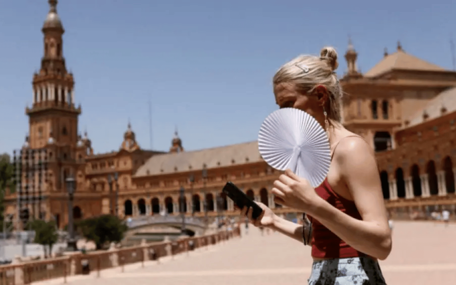 Mulher usando leque em uma pra&ccedil;a durante dia de calor intenso