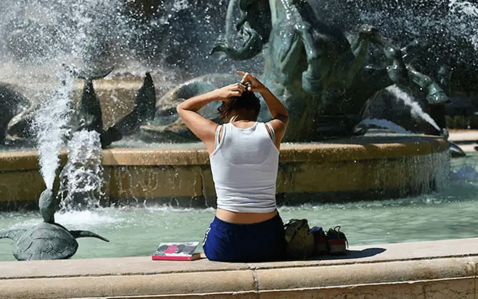 Mulher descansando perto de uma fonte em dia de calor durante a viagem