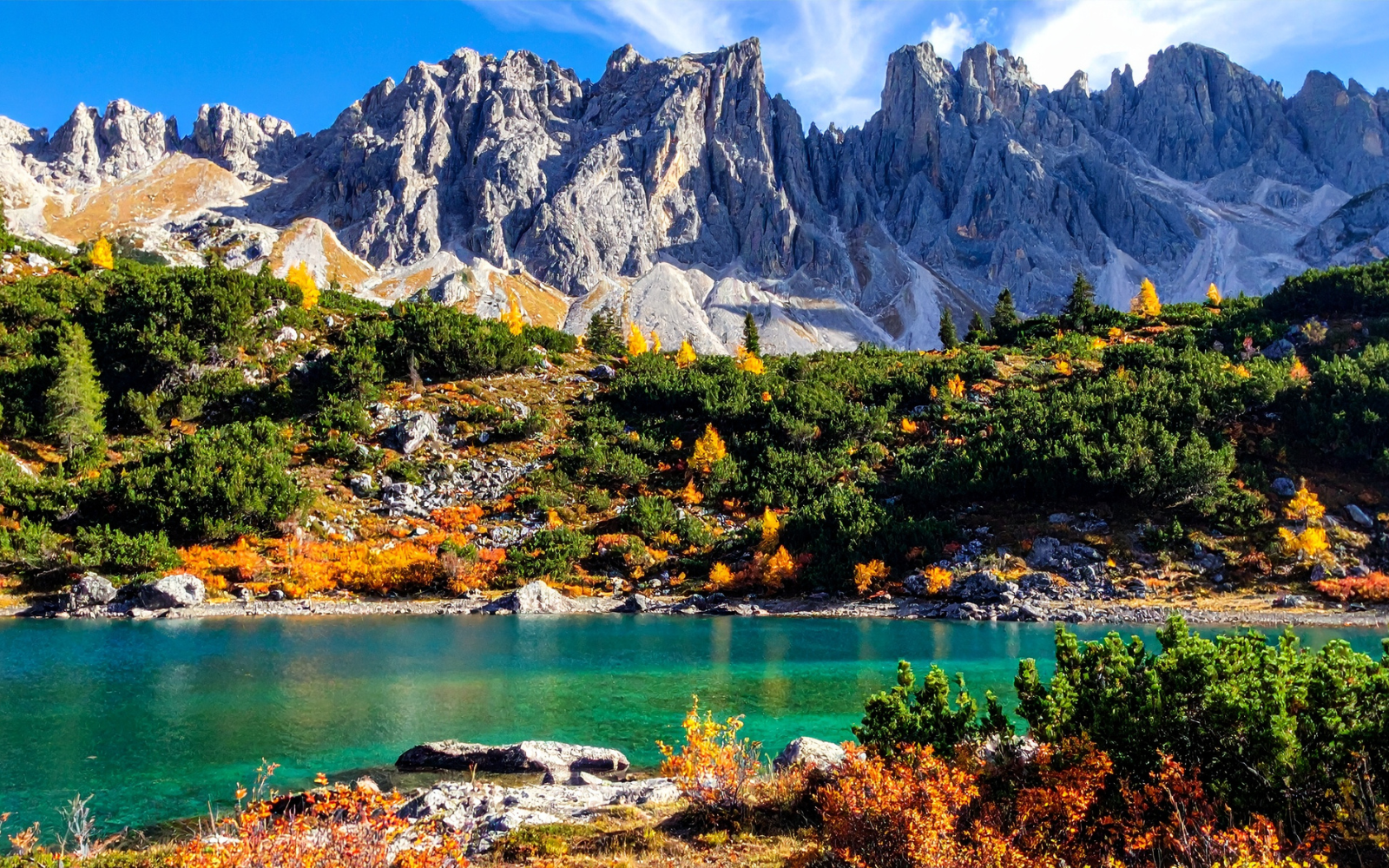 Lago cristalino diante de montanhas rochosas nas Dolomitas
