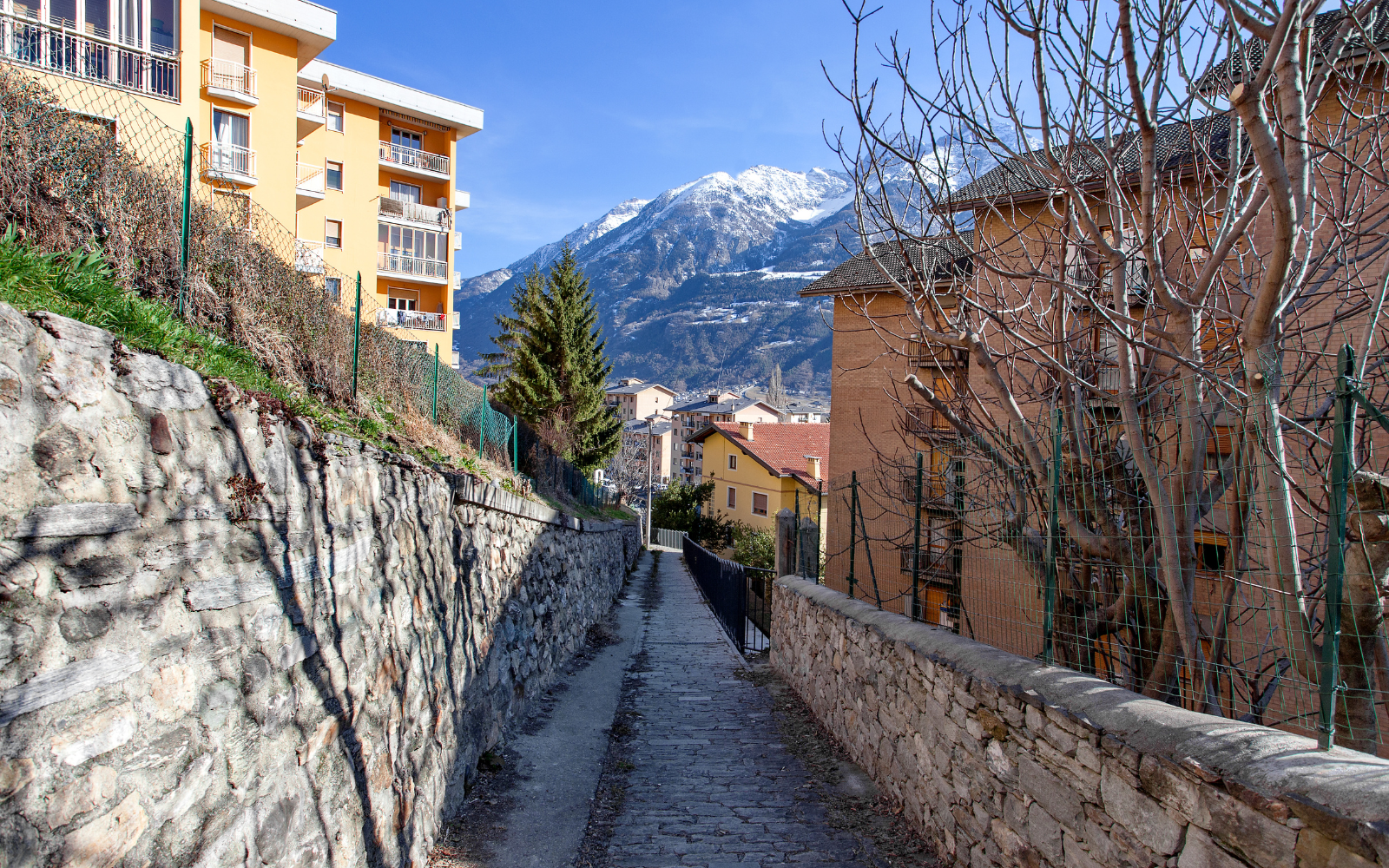 Rua de cidade alpina com montanha nevada ao fundo